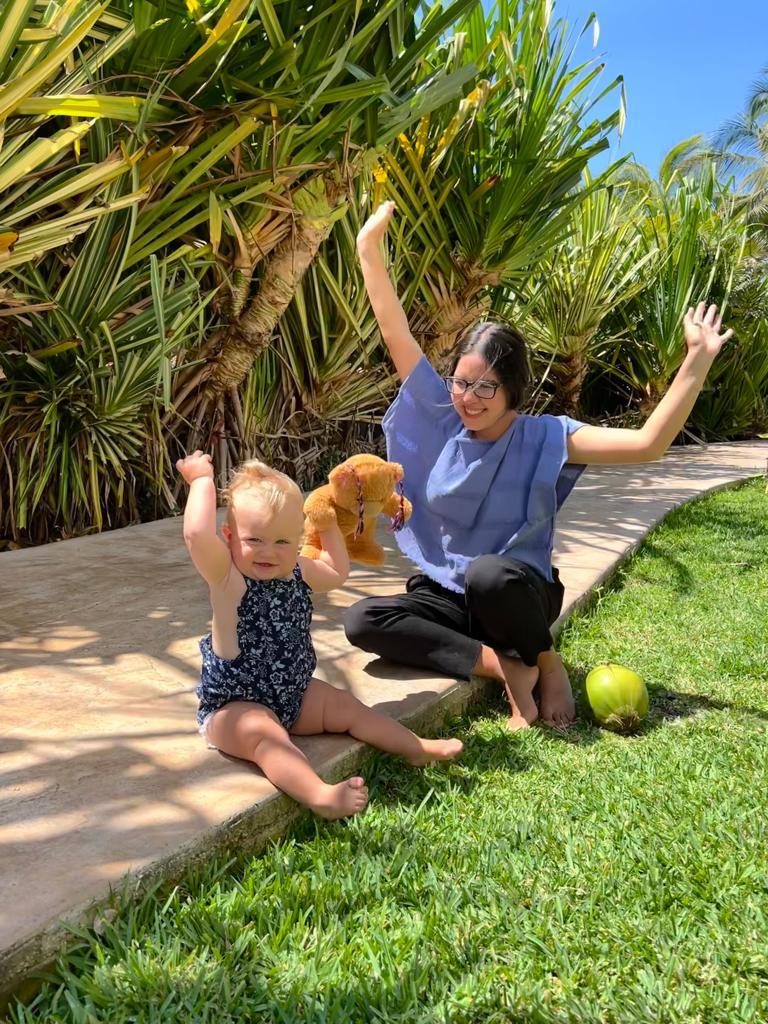 A We Care caregiver and a baby celebrating a small moment in a lush garden