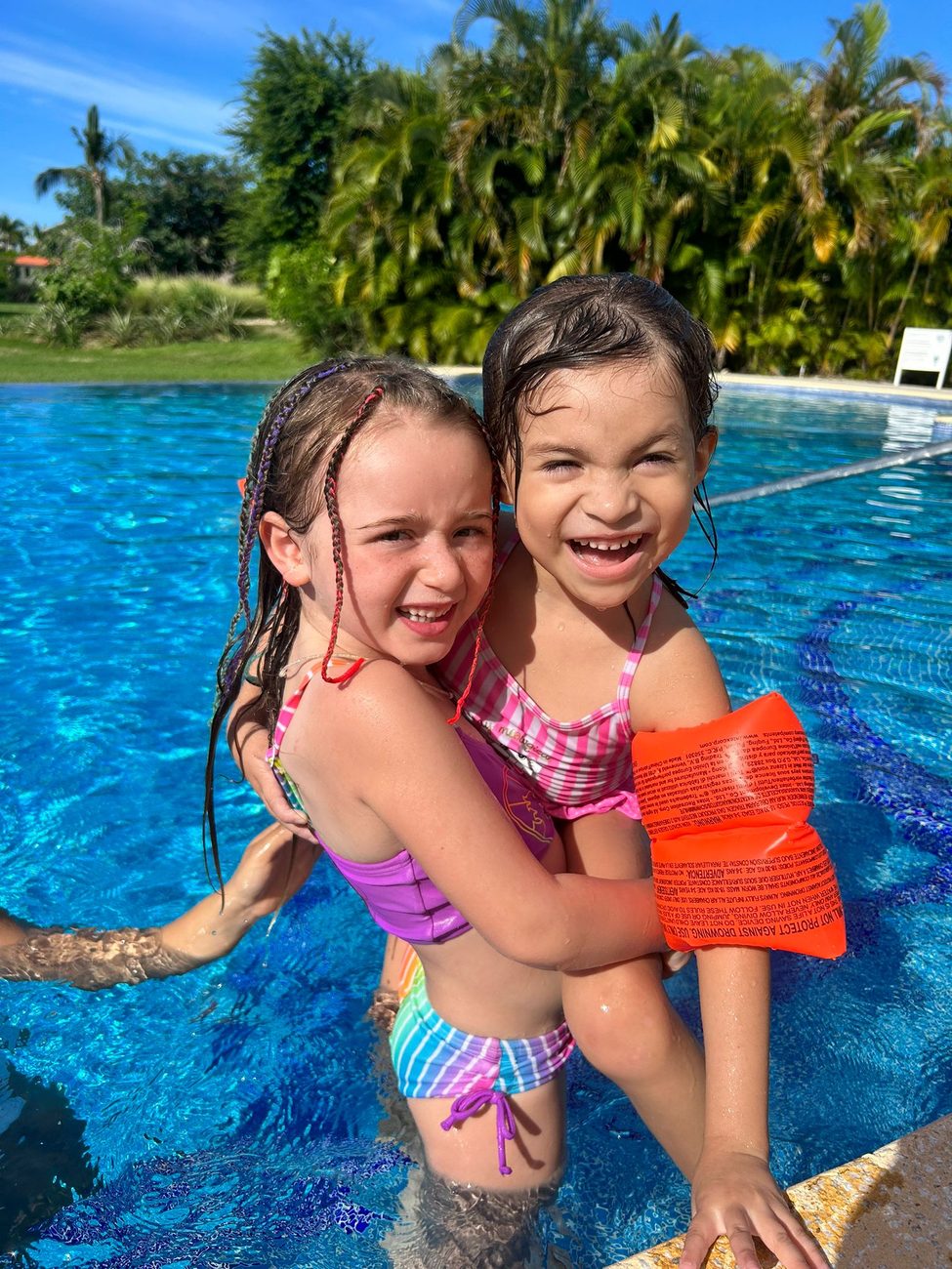 Two children laughing together in a bright turquoise villa pool