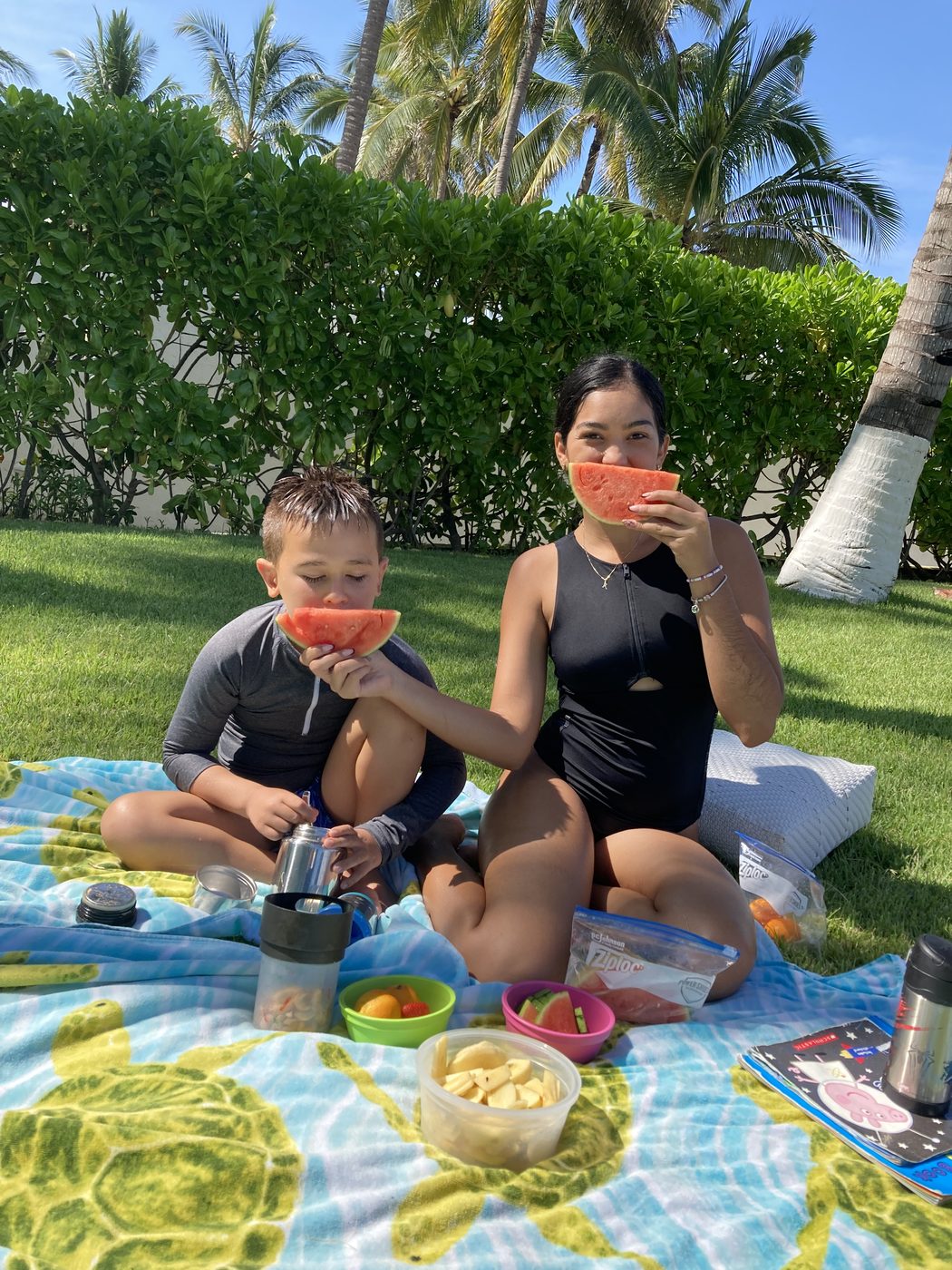 A We Care caregiver and a child sharing watermelon on a picnic blanket