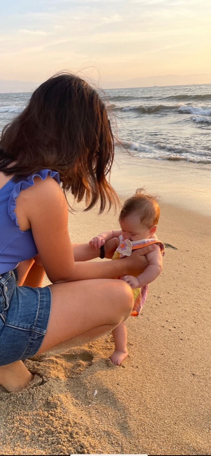 Nanny gently holding a baby at sunset on the beach