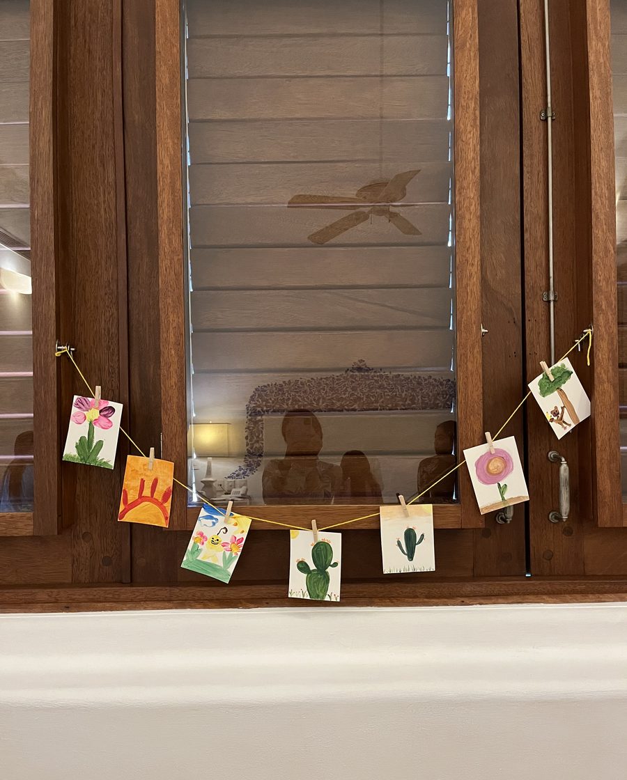 Children's paintings pegged to a line across a villa window